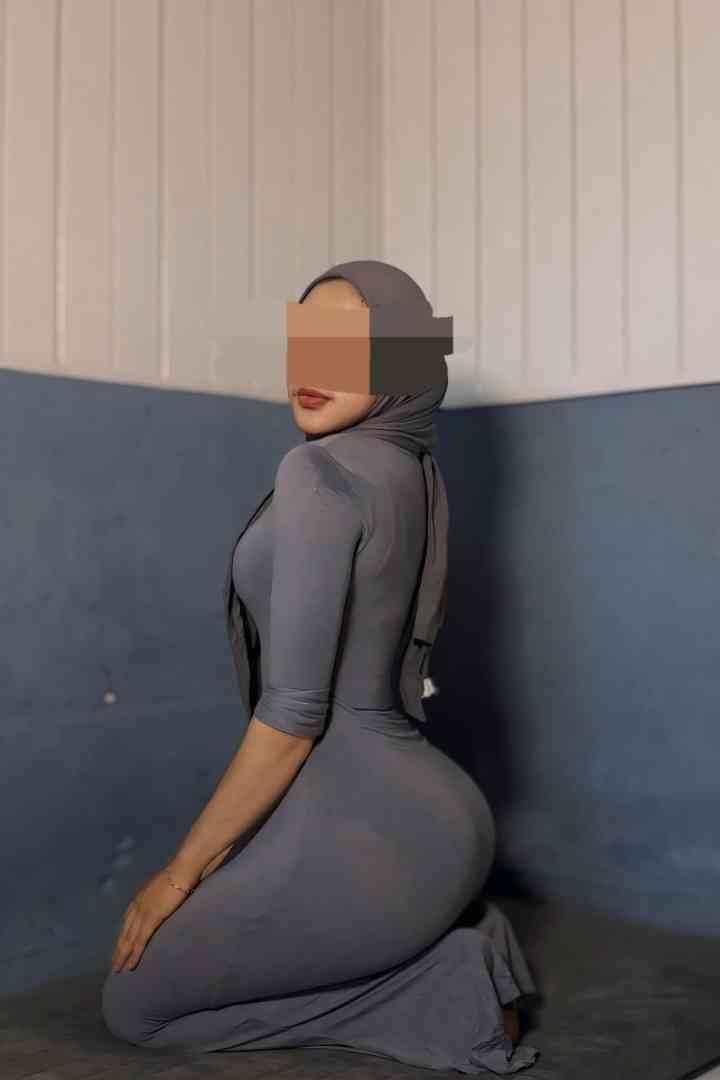 Woman in a hijab and form-fitting dress kneeling.