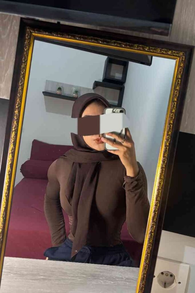 Mirror selfie of Dila, a Malay woman in a brown hijab and top, showing her style in KL.