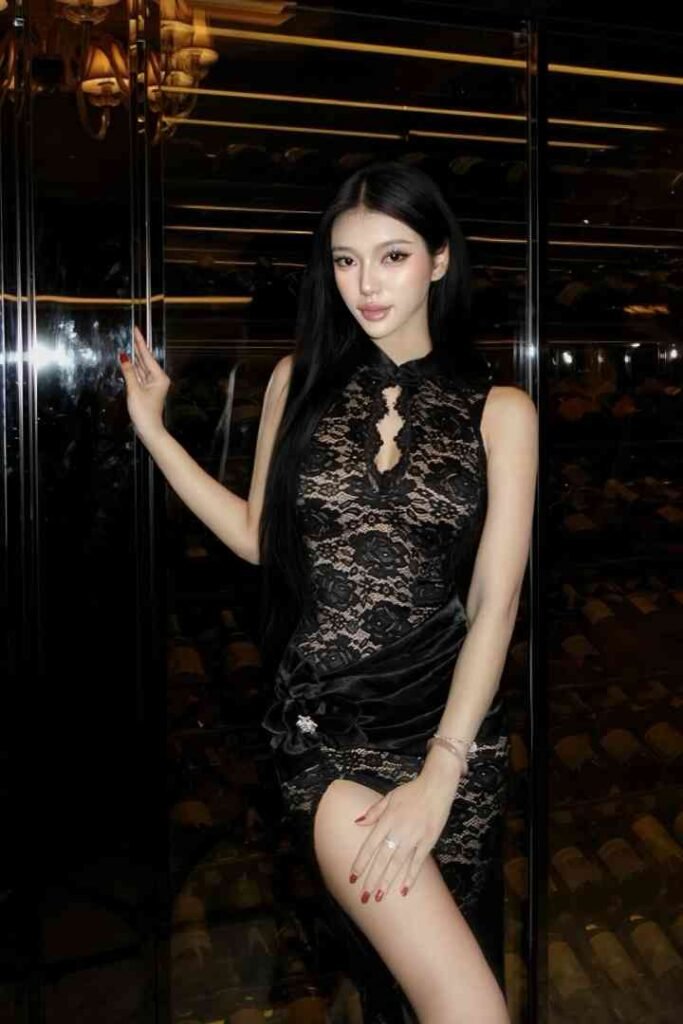 Erdene, a stunning Mongolian escort, poses in a black lace dress with a high slit.