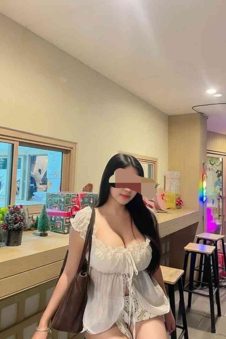 Woman in white top and shorts with a purse, standing near a counter with decorations.