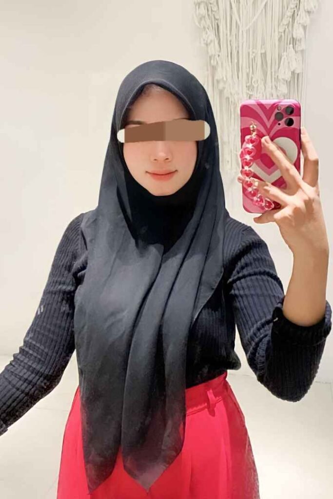 Malay woman in hijab taking a selfie with a pink phone case.